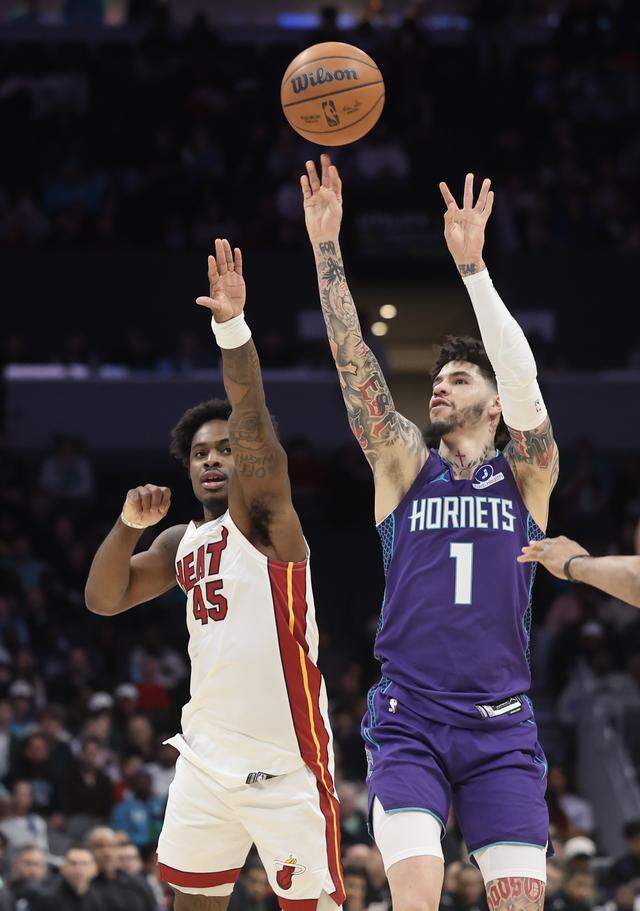 Charlotte Hornets guard LaMelo Ball (1) releases the ball over Miami Heat guard Davion Mitchell during the first quarter of the game Tuesday at Spectrum Center in Charlotte.